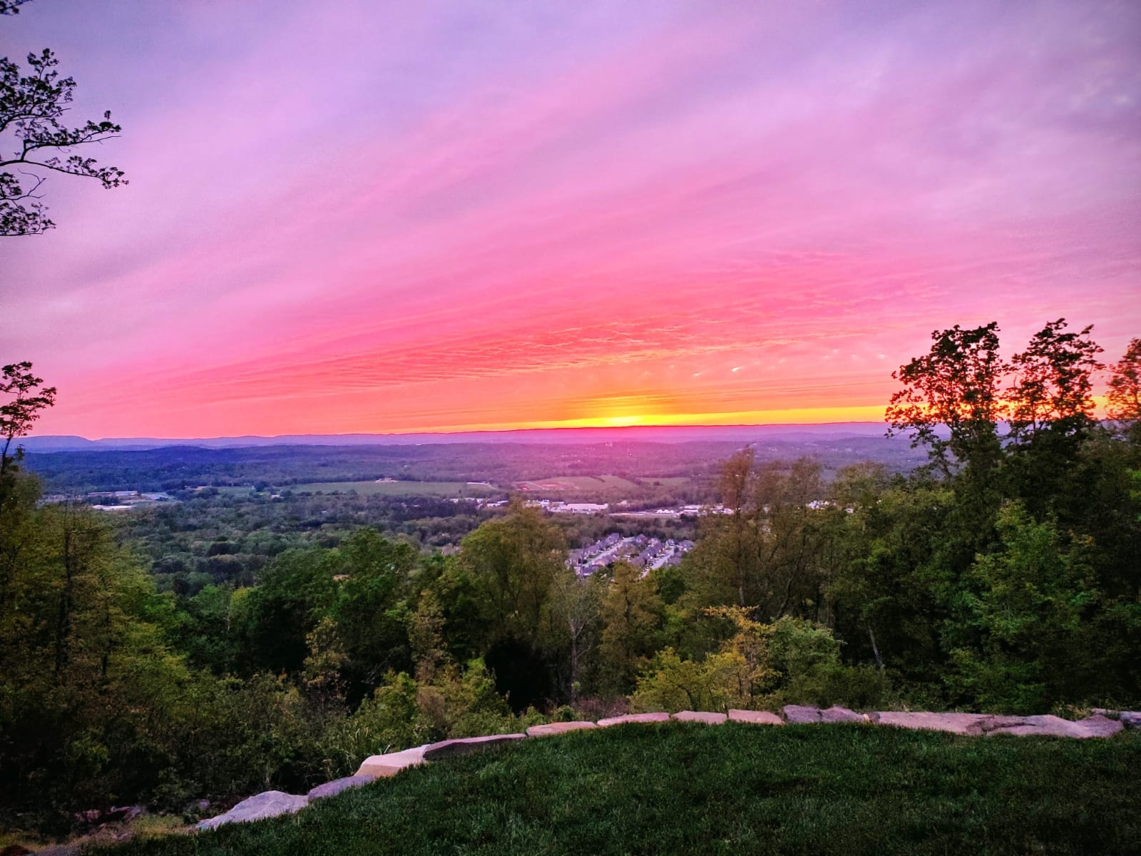 Vibrant pink and orange sunset over rolling green countryside
